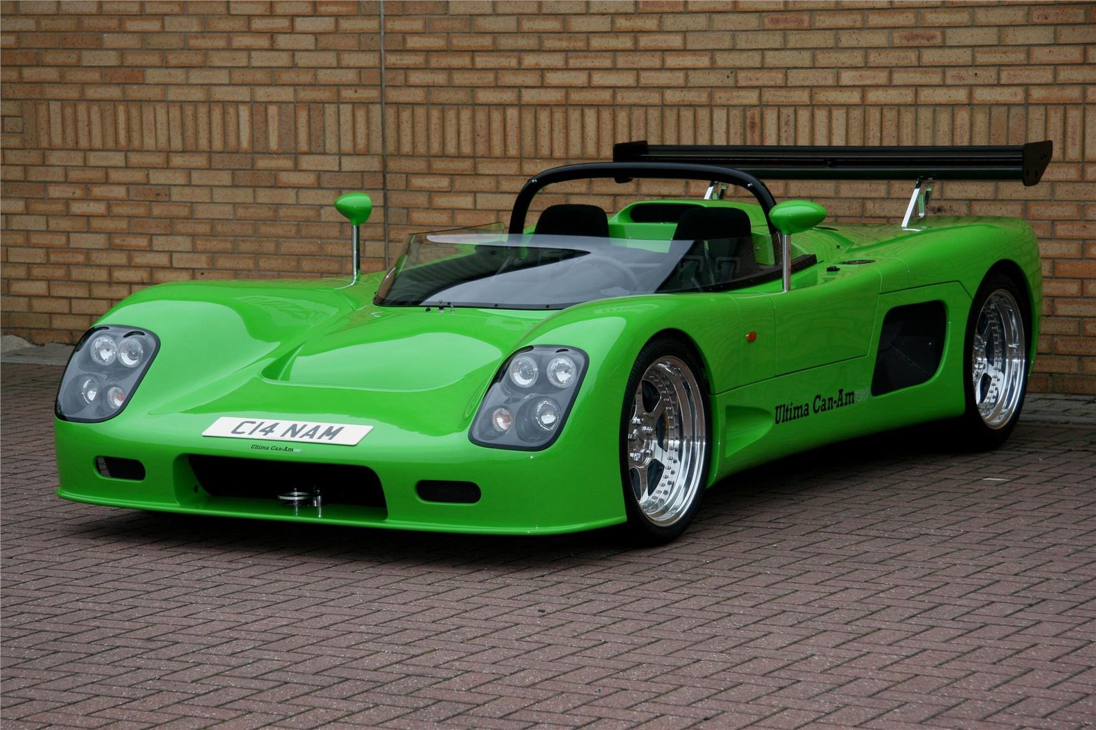 Green Ultima Can-Am parked beside a brick wall