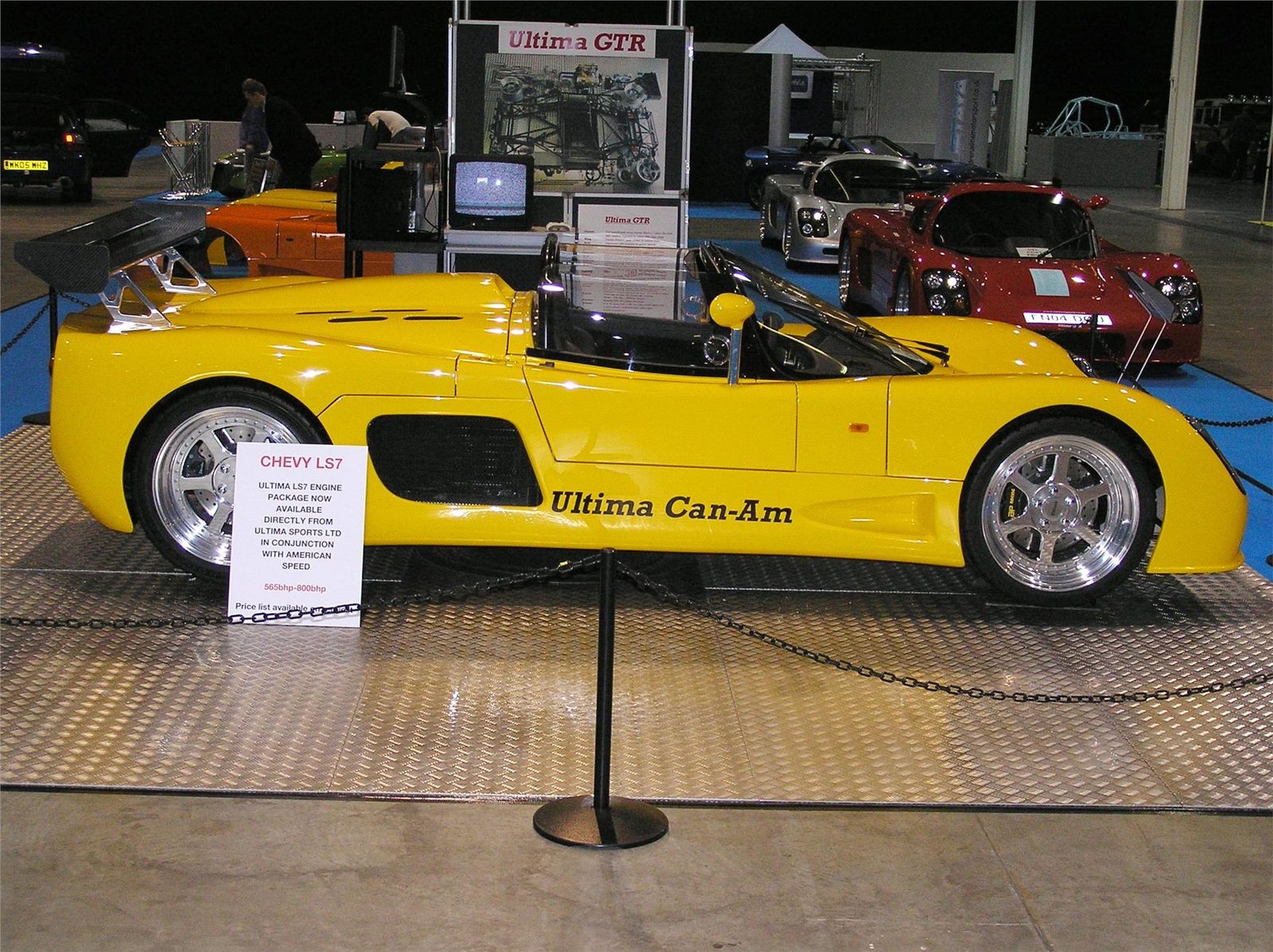 Yellow Ultima Can-Am displayed at a motor show