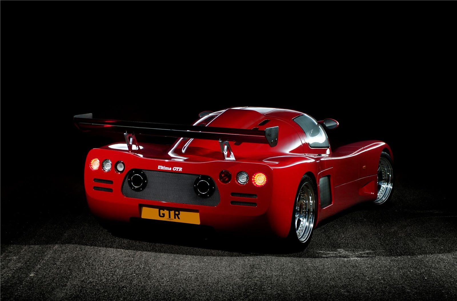 Red Ultima GTR seen from behind at night