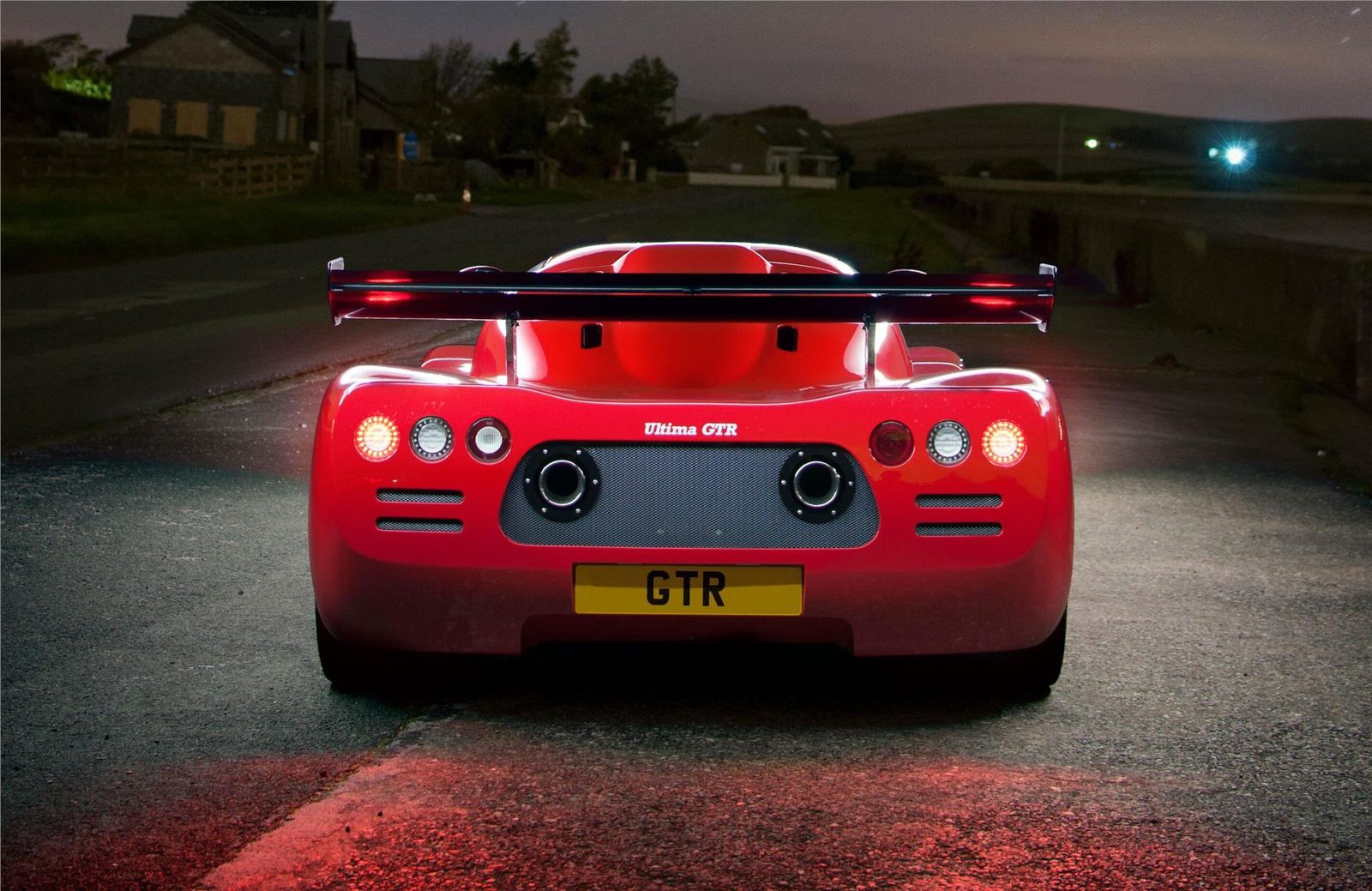 Red Ultima GTR seen from behind at dusk