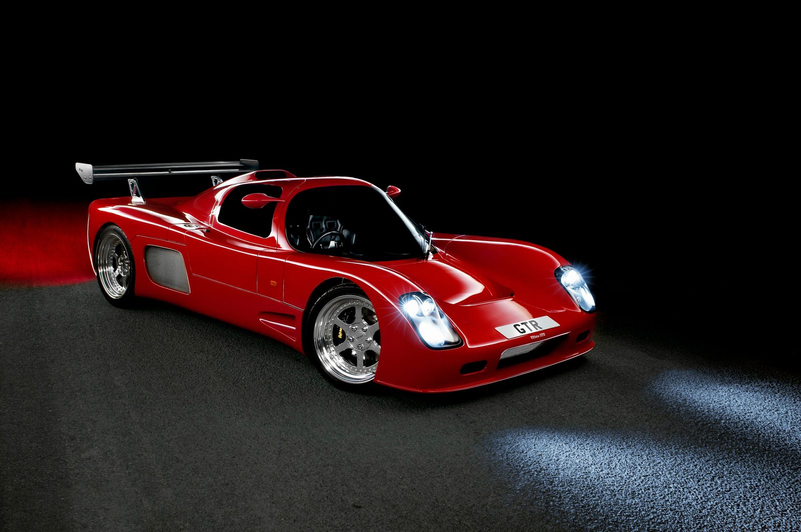 Red Ultima GTR in front three-quarter view at night