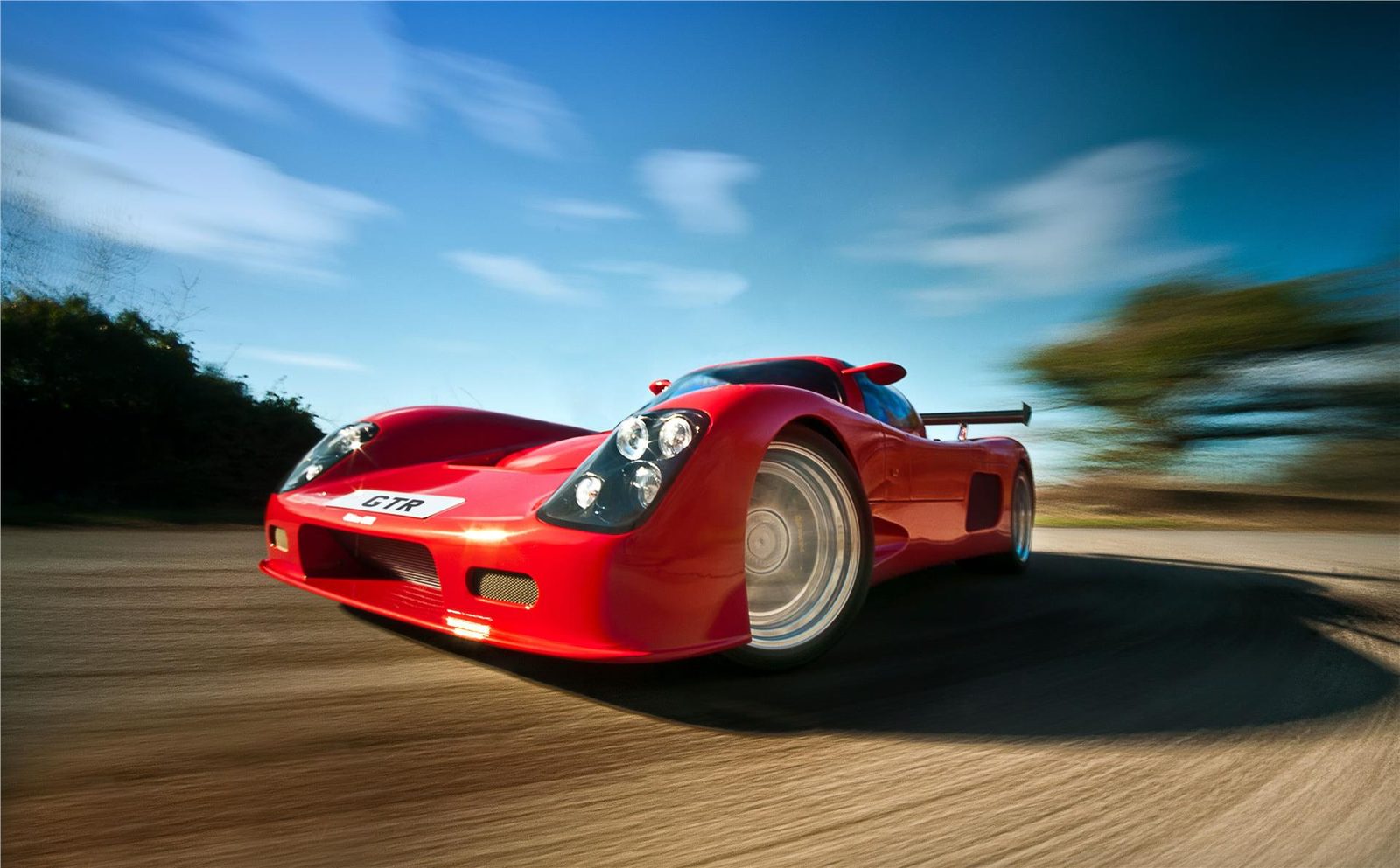 Red Ultima GTR photographed in motion on a road