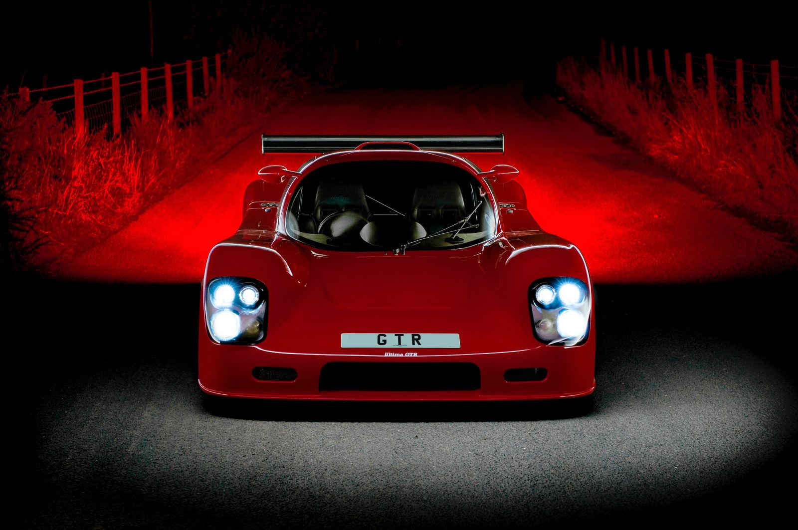 Red Ultima GTR photographed head-on at night