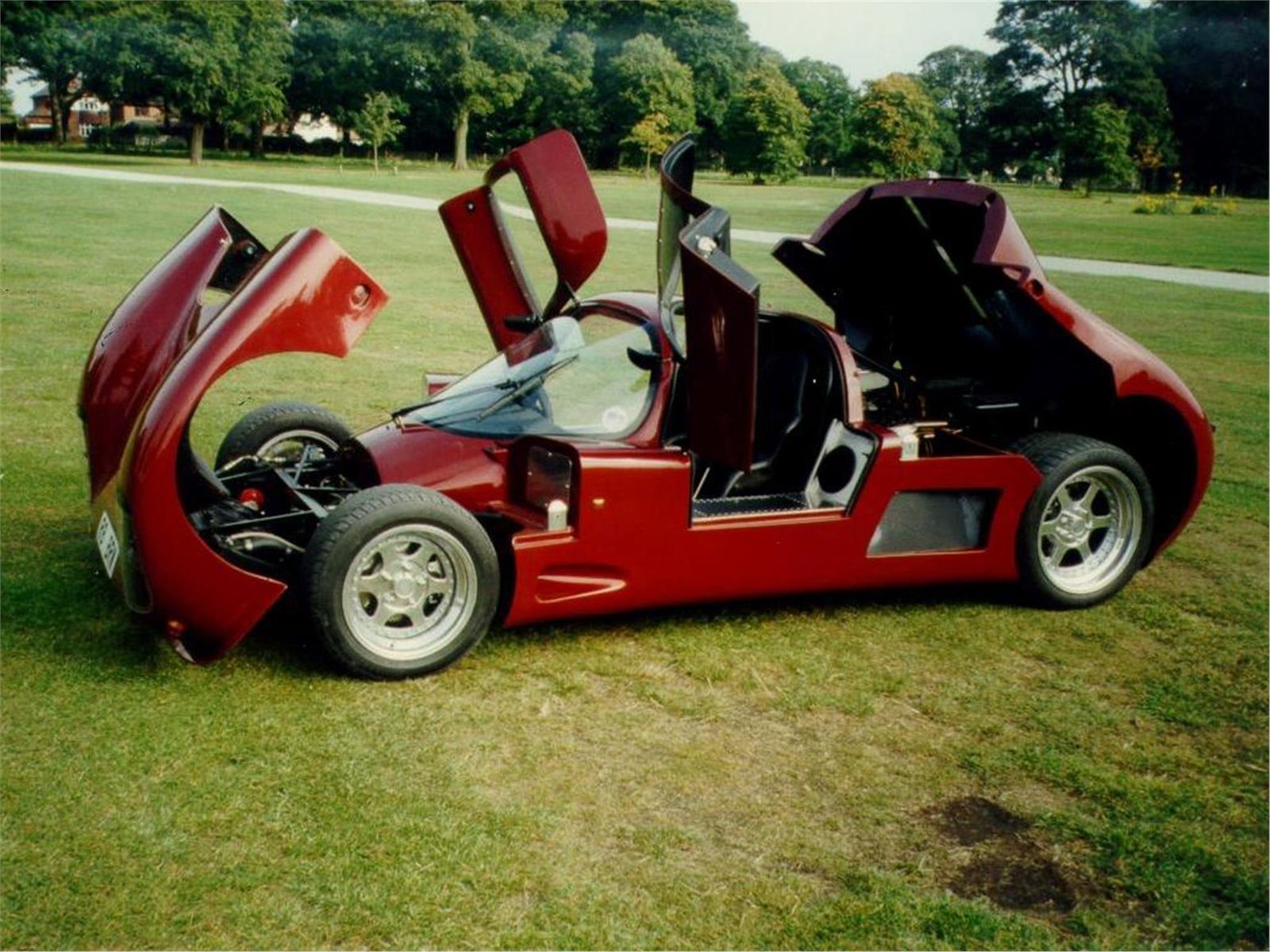 Red Ultima Sport with its body panels open on grass
