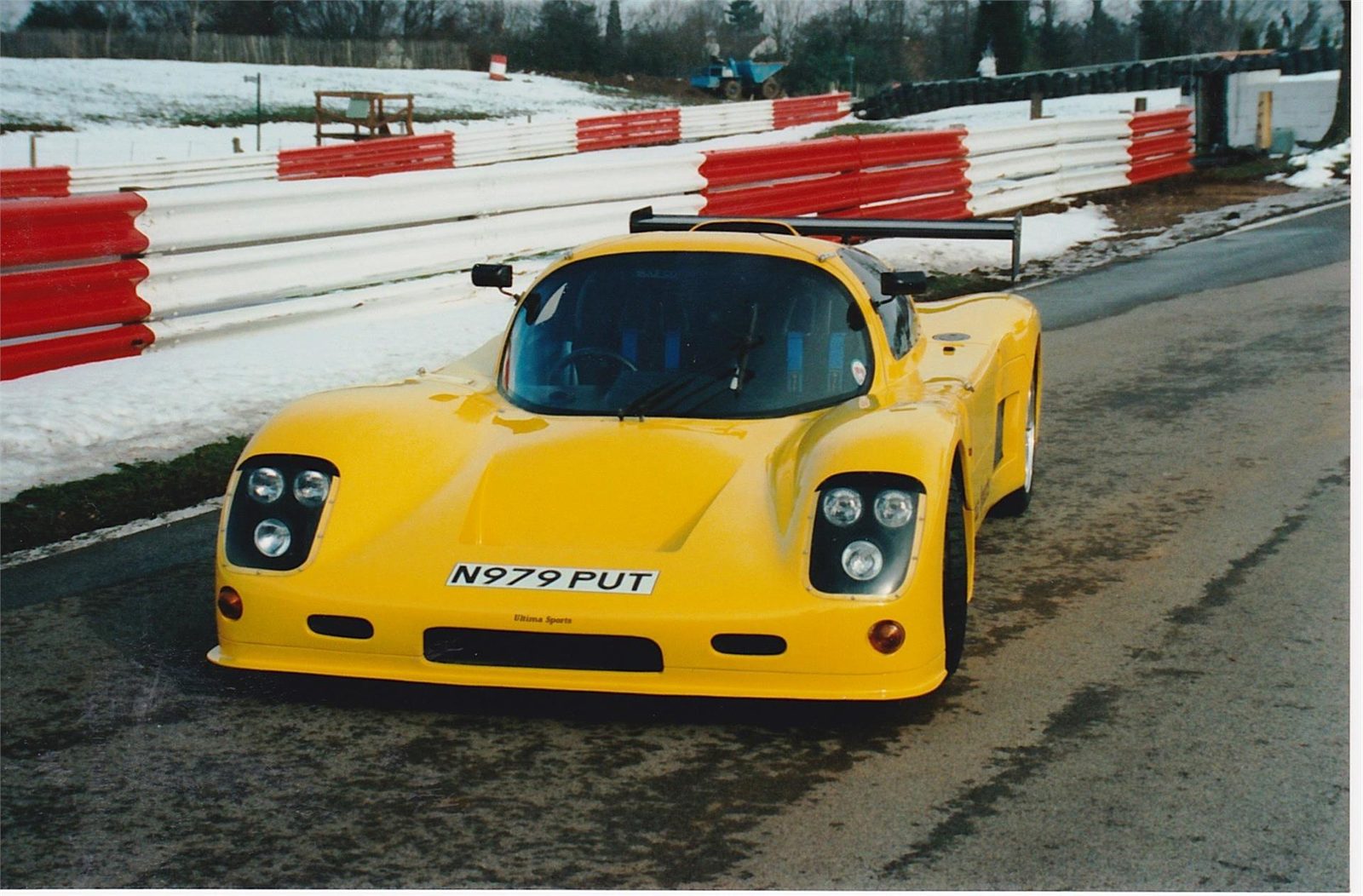 Yellow Ultima Sport facing the camera at a circuit