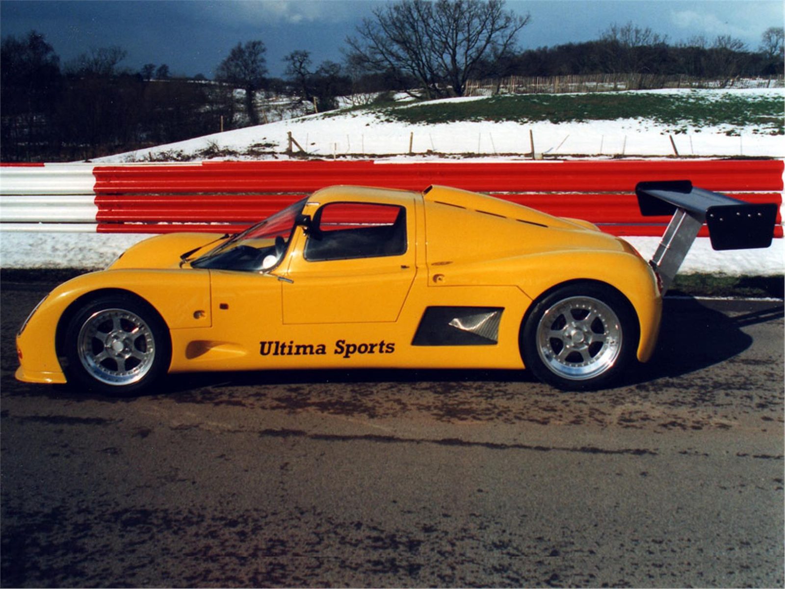 Yellow Ultima Sport beside a snowy circuit