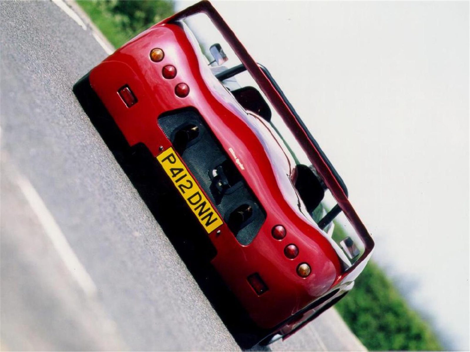 Rear view of a red Ultima Spyder on the road