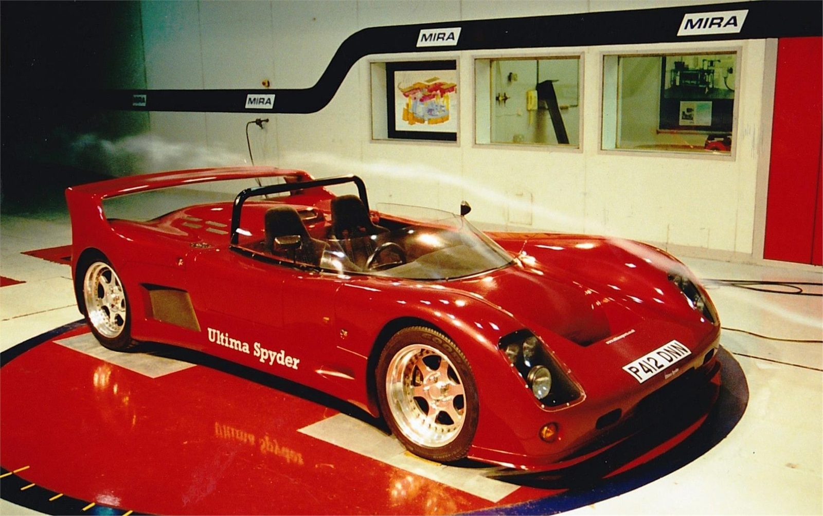 Red Ultima Spyder displayed at a motor show
