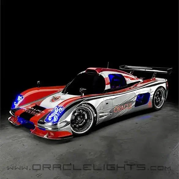 Three-quarter view of a red-and-white Ultima GTR with its blue headlamp halos lit.