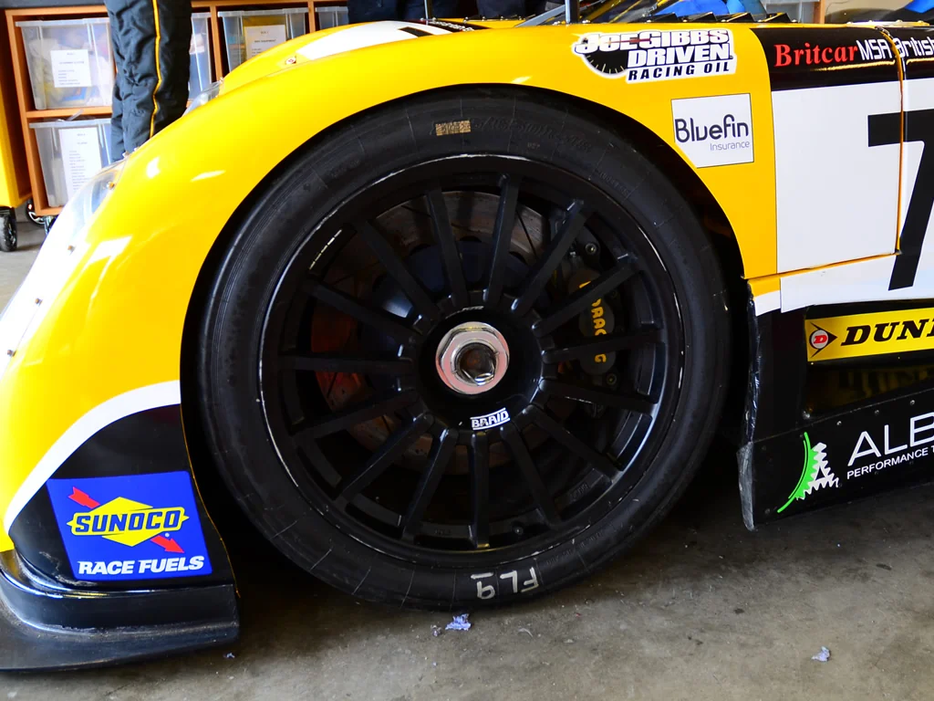 Brake kit behind a black Braid wheel on a yellow Ultima race car