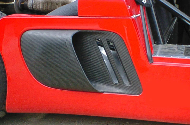 Driver-side carbon-fibre air intake fitted to a red Ultima body panel.