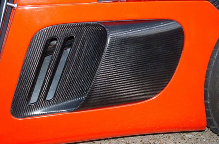Passenger-side carbon-fibre air intake fitted to a red Ultima body panel.