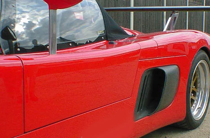 Side view of a red Ultima showing the passenger-side intake behind the door.